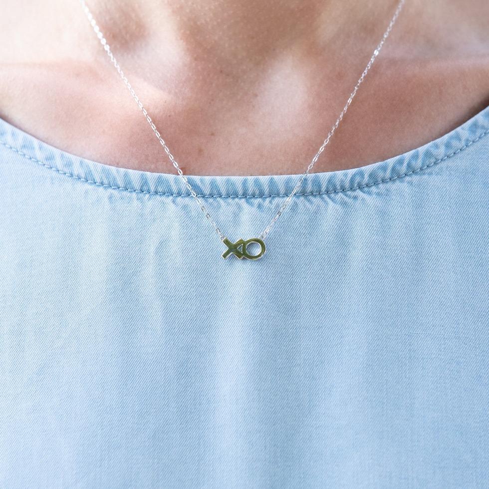 Woman wears a sterling silver necklace that features 'XO' in text .
