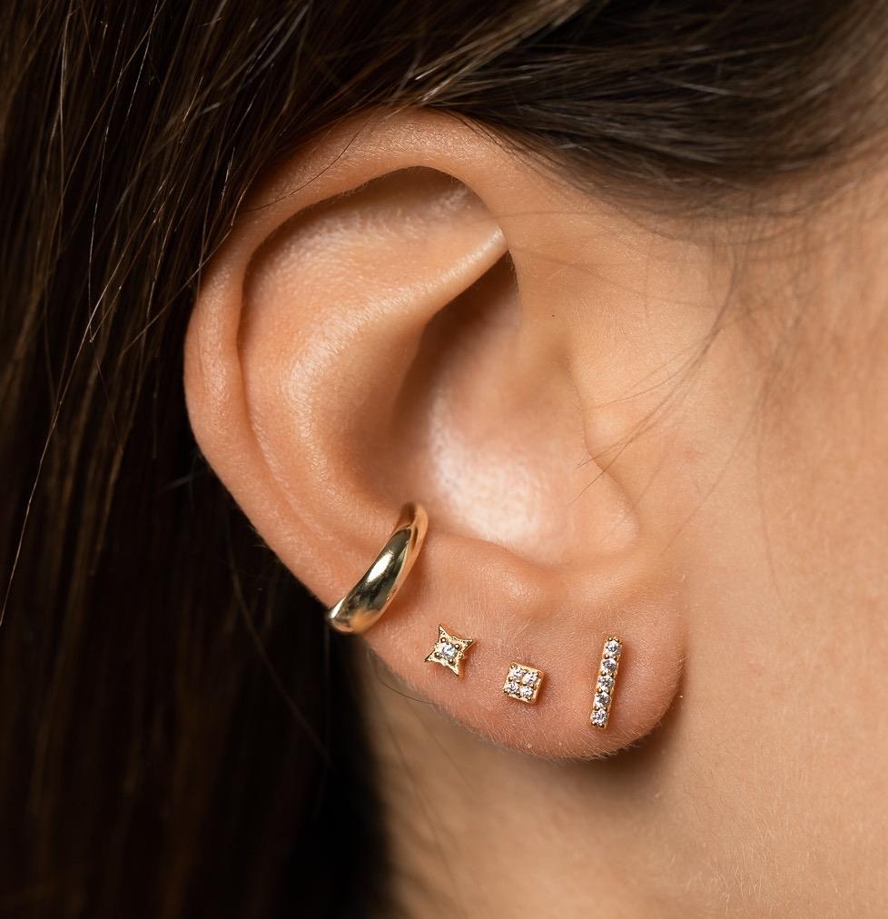 Photo of girl's ear with three small diamante studs and one 3mm gold plated, sterling silver ear cuff worn on conch.